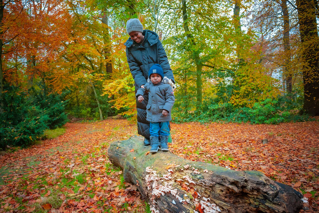 Foto van moeder met kind op boomstam in Park Vreugd en Rust
