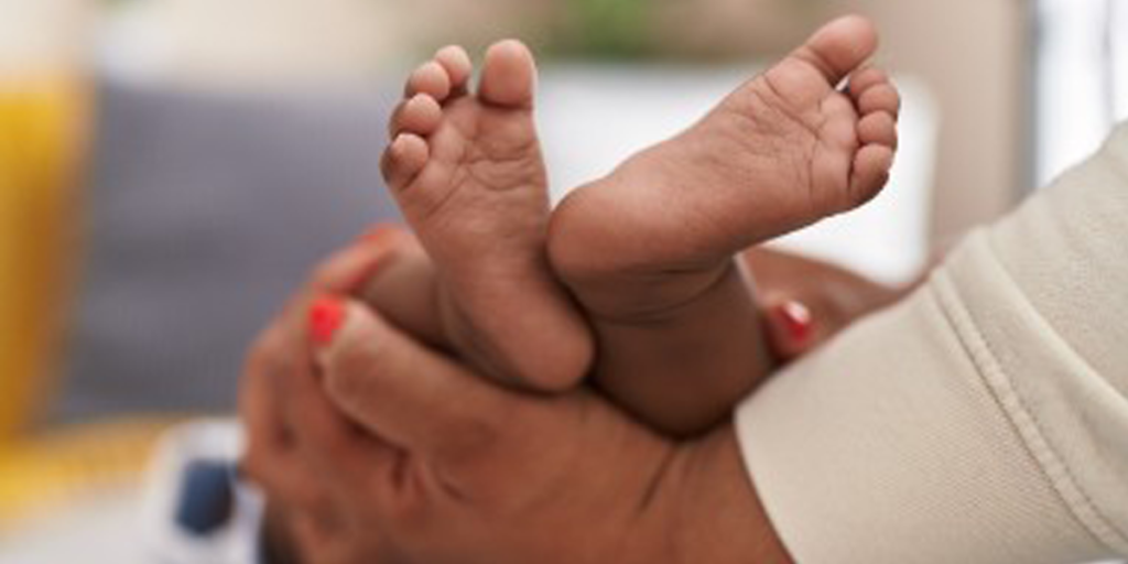 Voetjes van een baby in de handen van de moeder - Workshop Babymassage