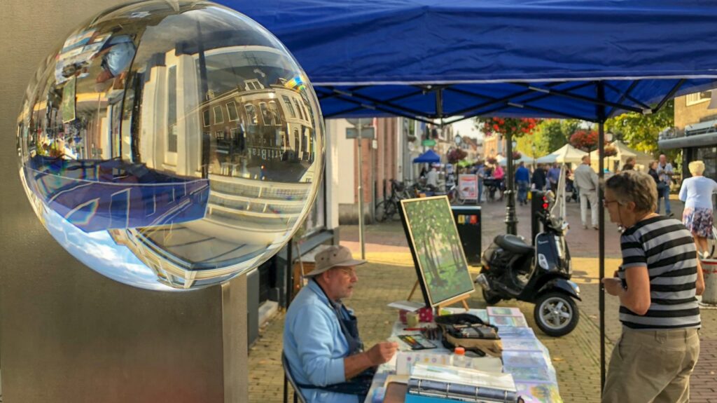 Man die zijn kunst verkoopt bij marktkraampje - De Voorburgse Rondgang